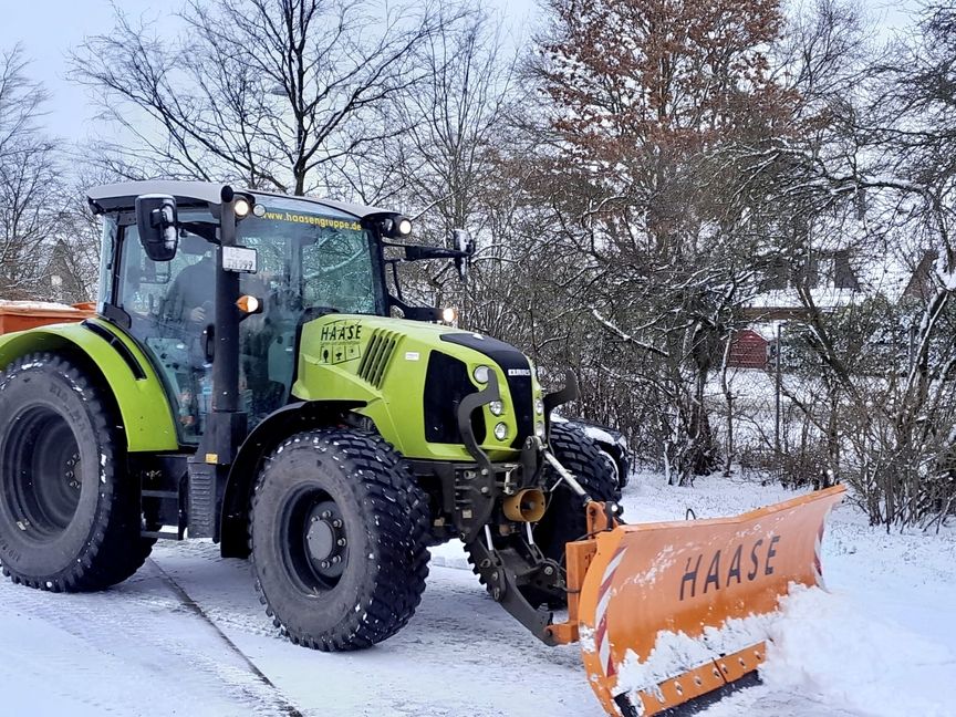 Ein Traktor mit angebauter Schneeschippe räumt Schnee weg